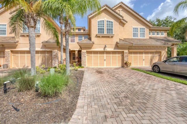 8228 Villa Grande Ct, Sarasota, FL 34243 - view of property featuring an attached garage, stucco siding, driveway, and stone siding