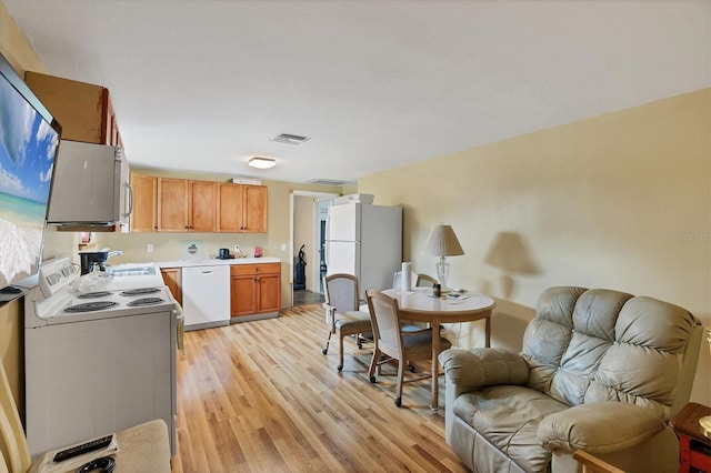 5412 Ulysses St, Port Charlotte, FL 33981 - kitchen featuring white appliances, light wood-style flooring, open floor plan, light countertops, and a sink