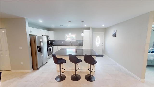 608 Saint Judes Dr, Longboat Key, FL 34228 - kitchen featuring appliances with stainless steel finishes, a sink, dark countertops, a kitchen bar, and decorative backsplash