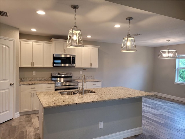 134 Swan Dr, Rotonda West, FL 33947 - kitchen featuring appliances with stainless steel finishes, light wood finished floors, white cabinetry, recessed lighting, and decorative light fixtures