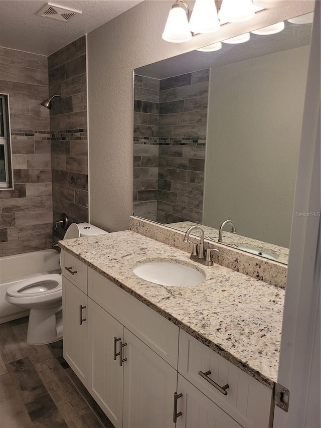 134 Swan Dr, Rotonda West, FL 33947 - full bath with vanity, wood finished floors, a textured wall, shower / washtub combination, and a textured ceiling