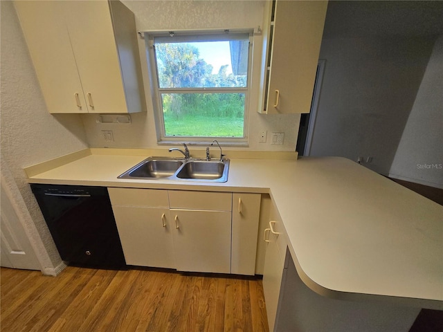4900 Hurley Ave, North Port, FL 34288 - kitchen with black dishwasher, light wood-style floors, light countertops, white cabinetry, and a textured wall