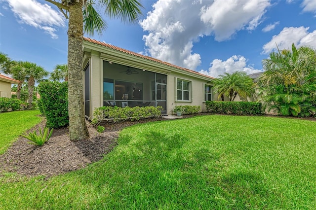 13051 Creekside Ln, Port Charlotte, FL 33953 - rear view of property with a yard, a sunroom, stucco siding, a tiled roof, and ceiling fan