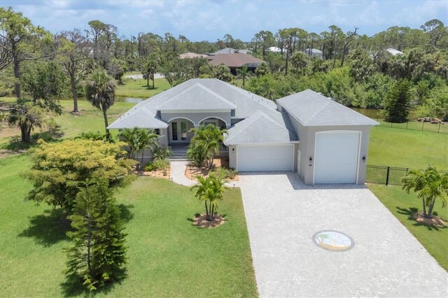 124 Cutlass Dr, Rotonda West, FL 33947 - view of front facade with a garage, decorative driveway, french doors, view of wooded area, and stucco siding