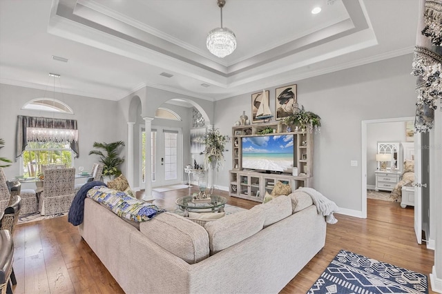 124 Cutlass Dr, Rotonda West, FL 33947 - living area with decorative columns, arched walkways, a tray ceiling, a chandelier, and crown molding