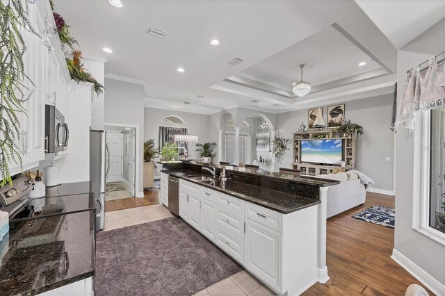 124 Cutlass Dr, Rotonda West, FL 33947 - kitchen with open floor plan, stainless steel appliances, crown molding, arched walkways, and white cabinetry