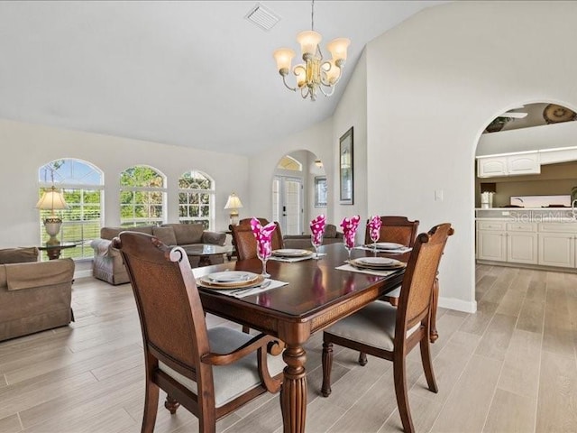 23 Pine Valley Ct, Rotonda West, FL 33947 - dining room with arched walkways, vaulted ceiling, a chandelier, and light wood-style floors
