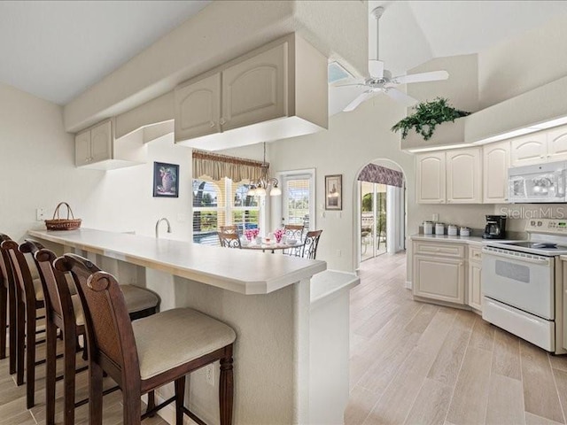 23 Pine Valley Ct, Rotonda West, FL 33947 - kitchen with white appliances, a breakfast bar, a peninsula, a ceiling fan, and arched walkways