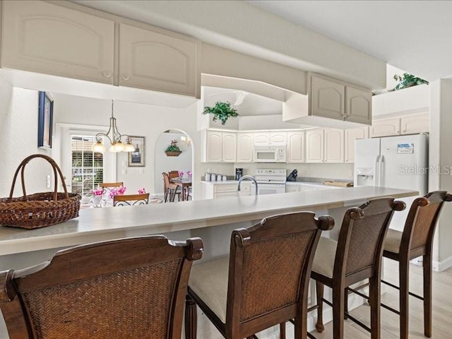23 Pine Valley Ct, Rotonda West, FL 33947 - kitchen featuring white appliances, a breakfast bar, a chandelier, light countertops, and white cabinets