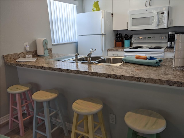 2373 N Beach Rd Unit 1C, Englewood, FL 34223 - kitchen featuring white appliances, white cabinetry, and a kitchen bar