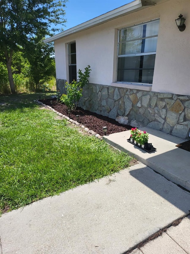 11216 Kimberly Ave Unit A & B, Englewood, FL 34224 - view of home's exterior with stucco siding, stone siding, and a lawn