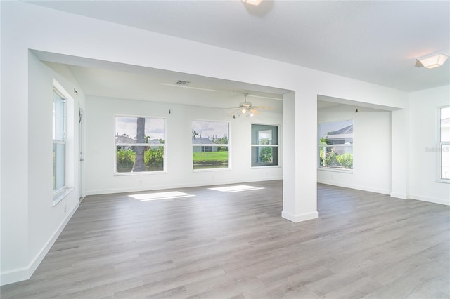 15 Bunker Pl, Rotonda West, FL 33947 - unfurnished living room featuring healthy amount of natural light, a ceiling fan, and wood finished floors