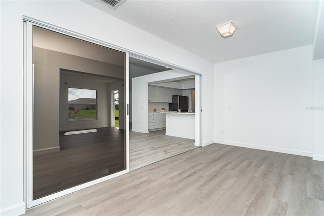 15 Bunker Pl, Rotonda West, FL 33947 - unfurnished living room with light wood-style flooring and a textured ceiling