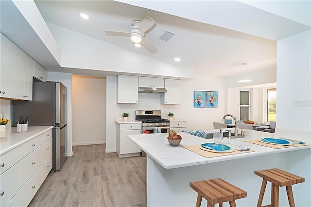 15 Bunker Pl, Rotonda West, FL 33947 - kitchen with appliances with stainless steel finishes, under cabinet range hood, a kitchen bar, white cabinets, and recessed lighting
