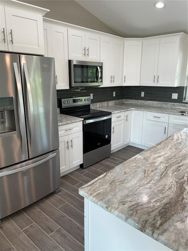 329 Overbrook St, Port Charlotte, FL 33954 - kitchen featuring appliances with stainless steel finishes, wood tiled floors, lofted ceiling, backsplash, and white cabinetry