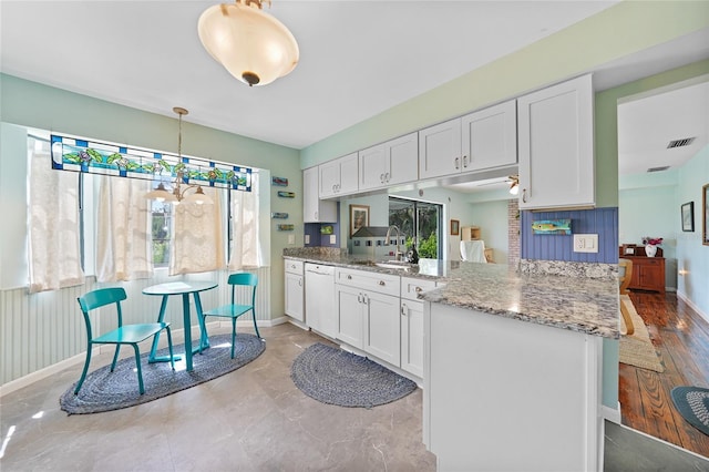 7690 Castleberry Ter, Englewood, FL 34224 - kitchen with a peninsula, white cabinets, white dishwasher, and light stone countertops