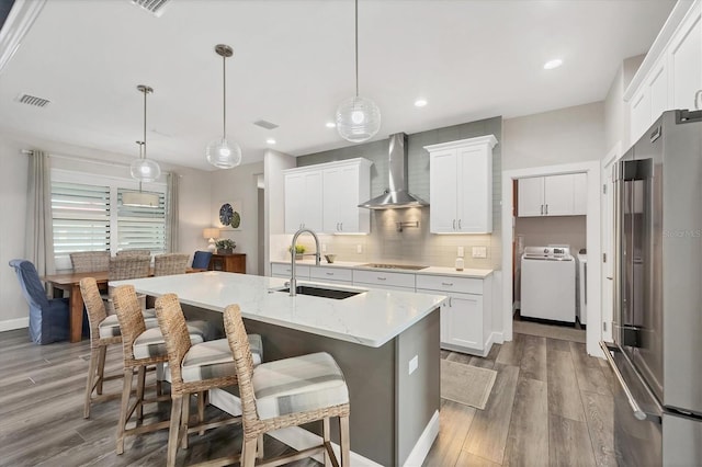 1269 N Lavina St, North Port, FL 34286 - kitchen featuring high end refrigerator, wall chimney range hood, black electric stovetop, decorative backsplash, and wood finished floors