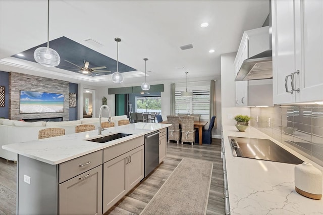 1269 N Lavina St, North Port, FL 34286 - kitchen with stainless steel dishwasher, open floor plan, black electric stovetop, light wood finished floors, and light stone countertops