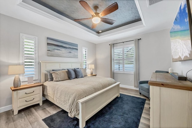 1269 N Lavina St, North Port, FL 34286 - bedroom featuring a raised ceiling, light wood-style flooring, multiple windows, and a ceiling fan