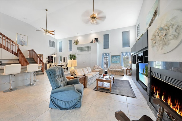 196 Lecturn St, Port Charlotte, FL 33954 - living area featuring a towering ceiling, a ceiling fan, stairs, light tile patterned flooring, and a warm lit fireplace