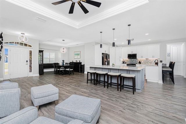 1119 Boundary Blvd, Rotonda West, FL 33947 - living area featuring a raised ceiling, light wood-style flooring, crown molding, ceiling fan, and recessed lighting