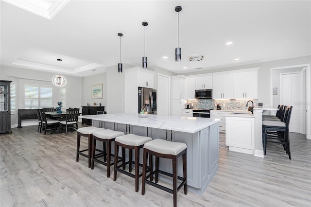 1119 Boundary Blvd, Rotonda West, FL 33947 - kitchen featuring appliances with stainless steel finishes, light wood-type flooring, a kitchen breakfast bar, backsplash, and crown molding