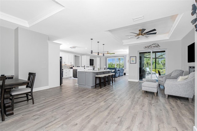 1119 Boundary Blvd, Rotonda West, FL 33947 - living area with a tray ceiling, a ceiling fan, light wood-type flooring, and crown molding