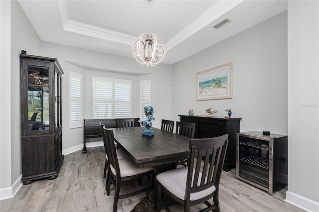 1119 Boundary Blvd, Rotonda West, FL 33947 - dining room with beverage cooler, a chandelier, light wood finished floors, a raised ceiling, and crown molding