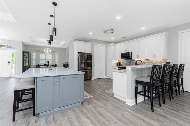 1119 Boundary Blvd, Rotonda West, FL 33947 - kitchen featuring black microwave, stainless steel fridge, light wood-style flooring, backsplash, and a raised ceiling