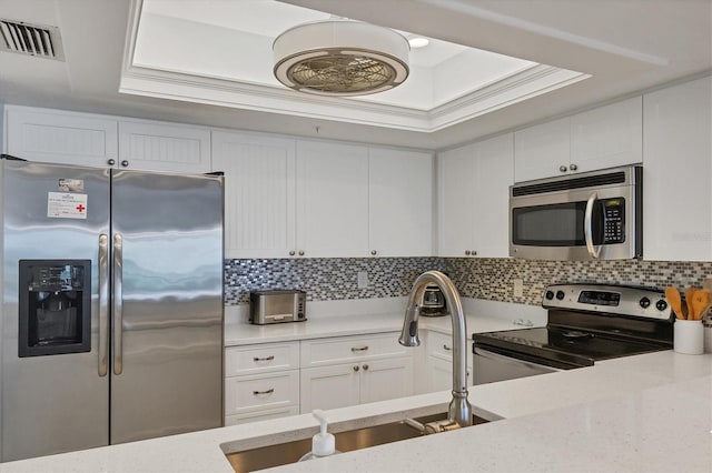 7554 Palm Island Dr S Unit 1813, Placida, FL 33946 - kitchen with appliances with stainless steel finishes, white cabinets, a raised ceiling, and backsplash