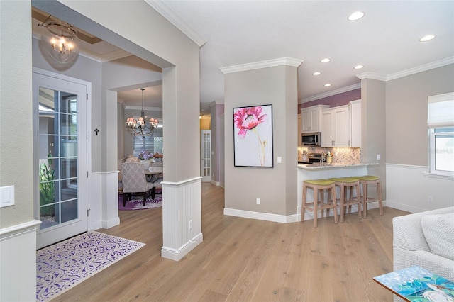 10487 Coquina Ct, Placida, FL 33946 - kitchen with a chandelier, ornamental molding, stainless steel appliances, light wood finished floors, and decorative backsplash