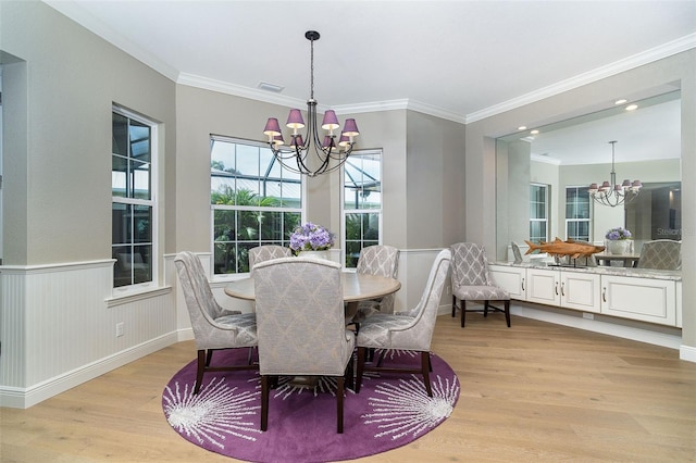 10487 Coquina Ct, Placida, FL 33946 - dining space with a chandelier, light wood finished floors, crown molding, and wainscoting