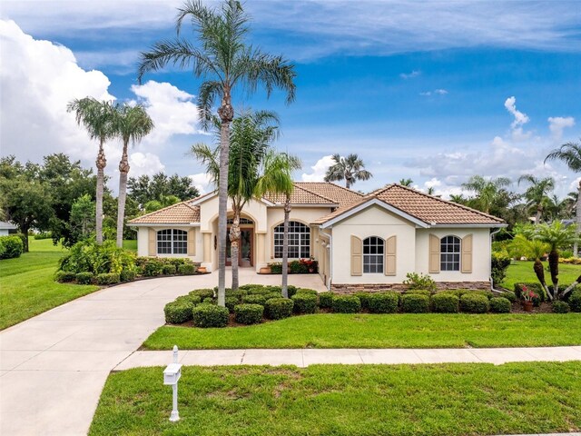 117 Abercrombie Ave, Englewood, FL 34223 - mediterranean / spanish-style house featuring stucco siding, a tiled roof, a front lawn, and concrete driveway