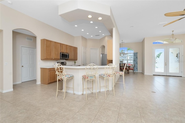 117 Abercrombie Ave, Englewood, FL 34223 - kitchen with stainless steel appliances, light tile patterned flooring, brown cabinetry, a kitchen bar, and light countertops