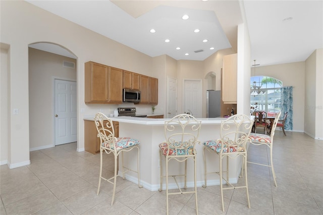 117 Abercrombie Ave, Englewood, FL 34223 - kitchen with stainless steel appliances, a breakfast bar area, arched walkways, light tile patterned floors, and a peninsula