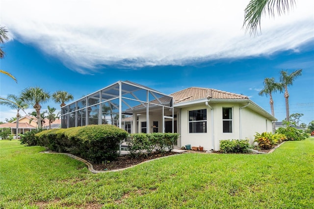 117 Abercrombie Ave, Englewood, FL 34223 - back of house with a lawn, a tiled roof, stucco siding, and glass enclosure