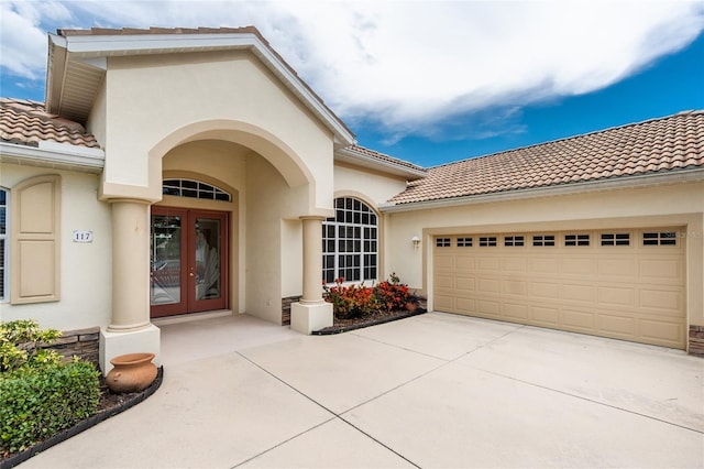 117 Abercrombie Ave, Englewood, FL 34223 - doorway to property with french doors, a tiled roof, stucco siding, a garage, and concrete driveway