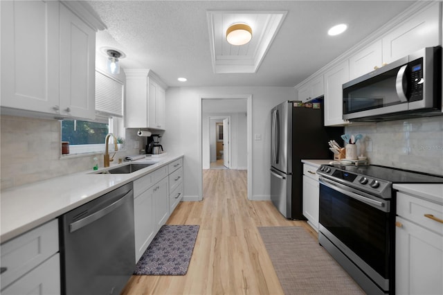 1730 Bluebird Ln, Englewood, FL 34224 - kitchen with appliances with stainless steel finishes, white cabinets, light wood-style flooring, tasteful backsplash, and light countertops