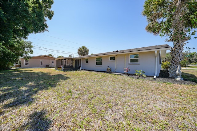 1730 Bluebird Ln, Englewood, FL 34224 - back of house featuring a lawn, stucco siding, and a sunroom