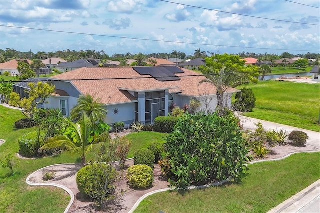 727 Rotonda Cir, Rotonda West, FL 33947 - view of front of home featuring a residential view, roof mounted solar panels, a front lawn, and roof with shingles