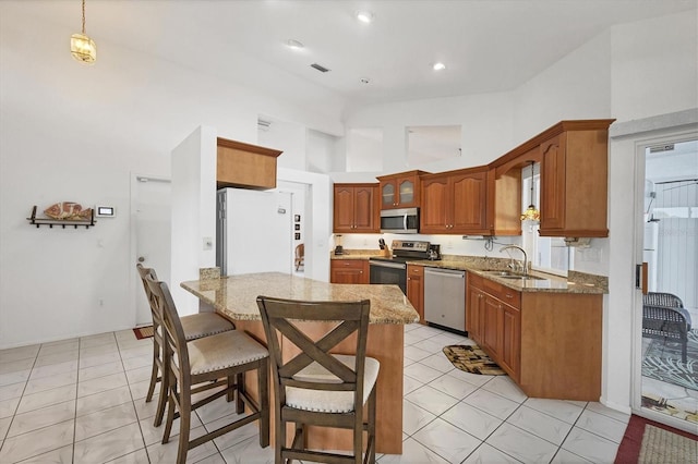 727 Rotonda Cir, Rotonda West, FL 33947 - kitchen with stainless steel appliances, a towering ceiling, light stone counters, a breakfast bar area, and brown cabinets