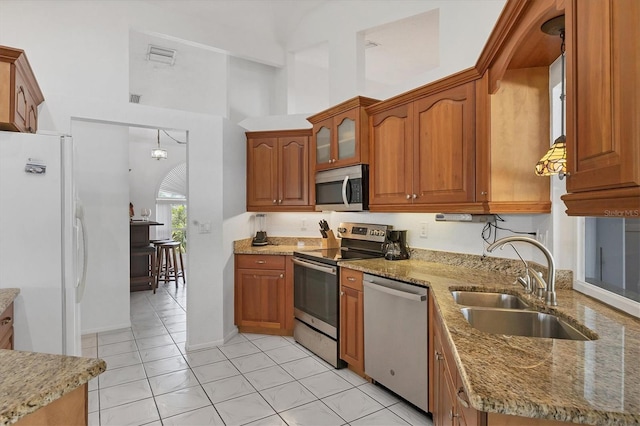 727 Rotonda Cir, Rotonda West, FL 33947 - kitchen featuring appliances with stainless steel finishes, brown cabinetry, light stone counters, light tile patterned floors, and a high ceiling