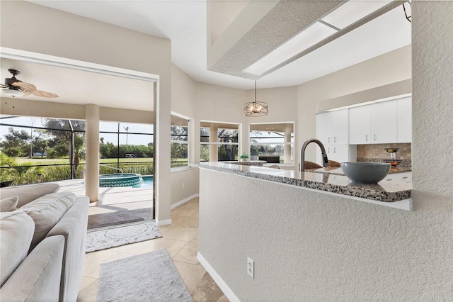 39 Pine Valley Ct, Rotonda West, FL 33947 - kitchen featuring dark stone counters, white cabinets, open floor plan, light tile patterned floors, and a peninsula