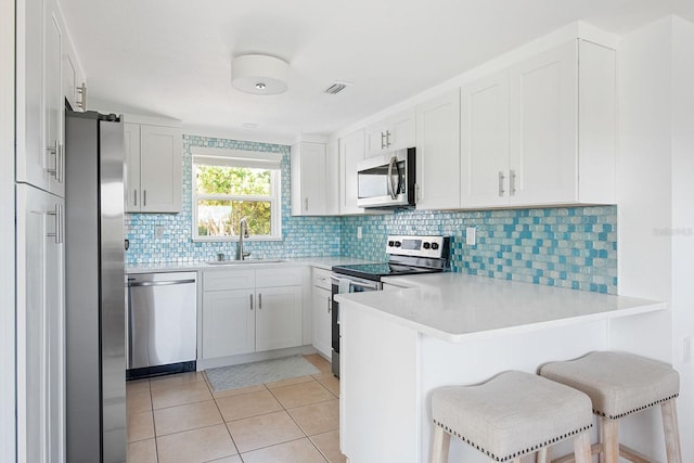 1060 Haste Ln, Englewood, FL 34223 - kitchen with stainless steel appliances, a peninsula, light countertops, light tile patterned floors, and decorative backsplash