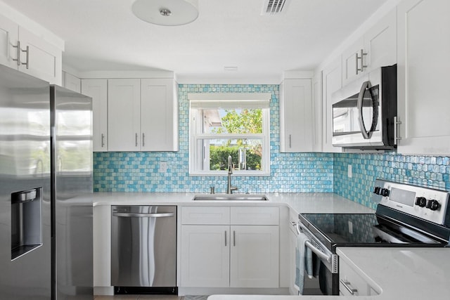 1060 Haste Ln, Englewood, FL 34223 - kitchen with stainless steel appliances, light countertops, backsplash, and white cabinets
