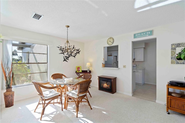 609 Deerwood Ave, Englewood, FL 34223 - dining area with a textured ceiling, a glass covered fireplace, plenty of natural light, a chandelier, and light colored carpet