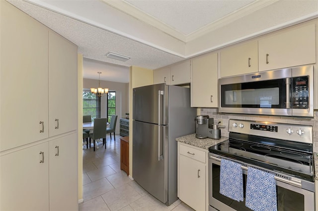 7218 Darlington St, Englewood, FL 34224 - kitchen featuring appliances with stainless steel finishes, cream cabinetry, a chandelier, tasteful backsplash, and light tile patterned floors