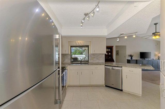 7218 Darlington St, Englewood, FL 34224 - kitchen featuring appliances with stainless steel finishes, rail lighting, a textured ceiling, tasteful backsplash, and light tile patterned flooring