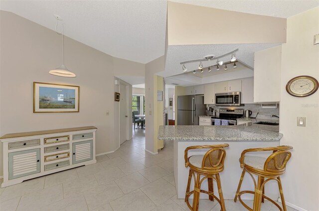 7218 Darlington St, Englewood, FL 34224 - kitchen featuring appliances with stainless steel finishes, a peninsula, a textured ceiling, decorative backsplash, and a kitchen bar