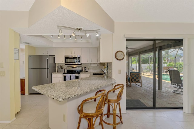 7218 Darlington St, Englewood, FL 34224 - kitchen with stainless steel appliances, a peninsula, light tile patterned floors, decorative backsplash, and a textured ceiling